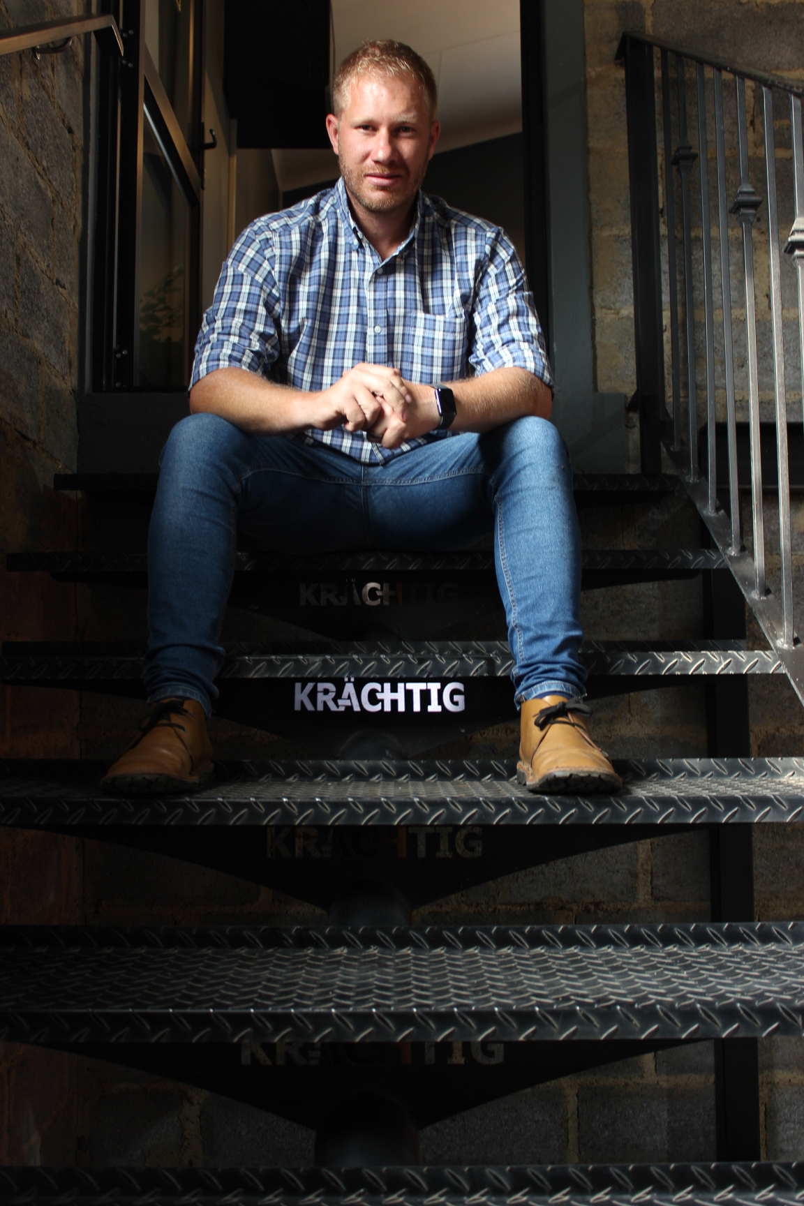 Portrait of a man seated on Krächtig-branded metal stairs.